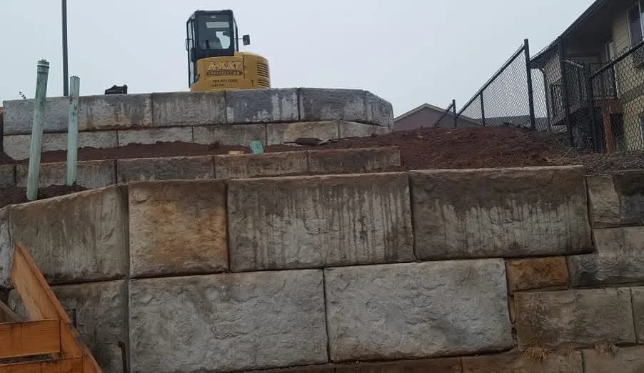 The A-KAT excavator parked on top of a large block retaining wall