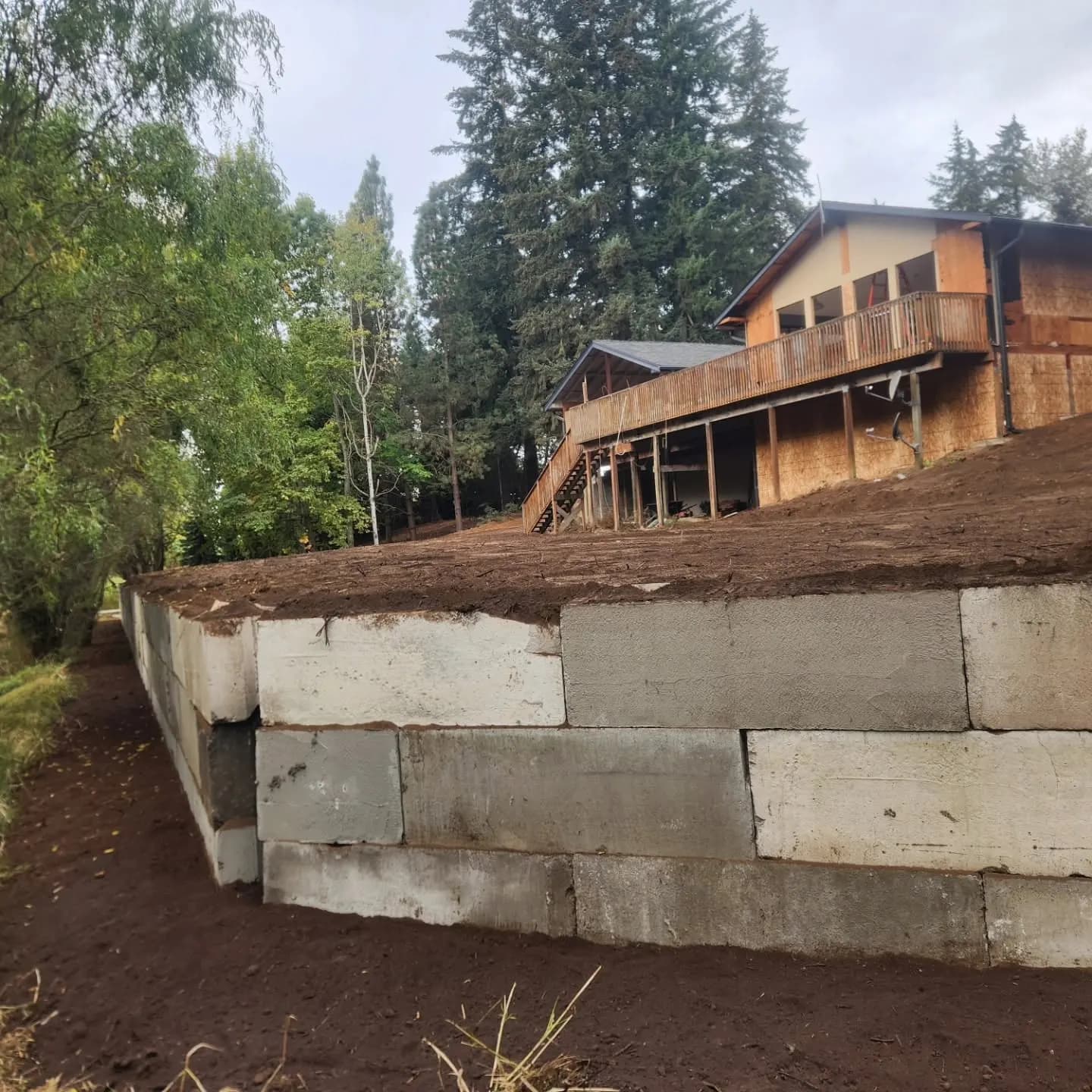 Concrete block retaining wall holding a level yard below a hillside home