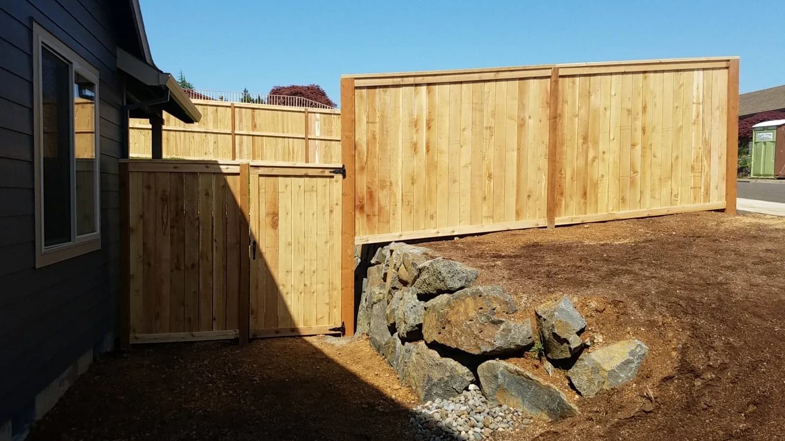 Cedar privacy fence and gate built above a boulder retaining wall